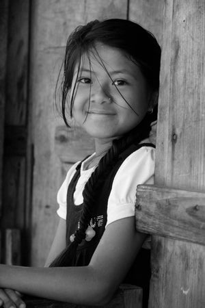 Jeune fille des Annapurnas au Népal, retour d’école, assise à la porte de sa maison